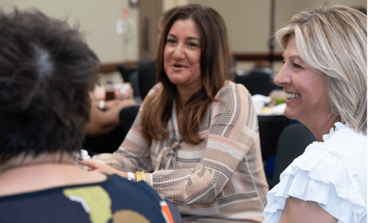Close up of women sitting at a table talking at a conference