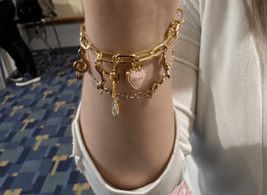 Woman holding up wrist to show charm bracelets.