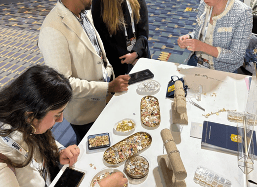 People selecting charms for their braceletsat a booth in the expo hall at a convention.