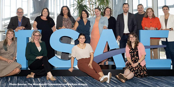 Group of people pose with large 3-d letters that spell TSAE.