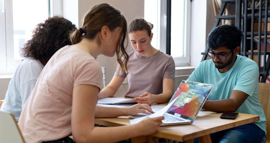 A group of diverse young professionals studying together on their laptops at a table.