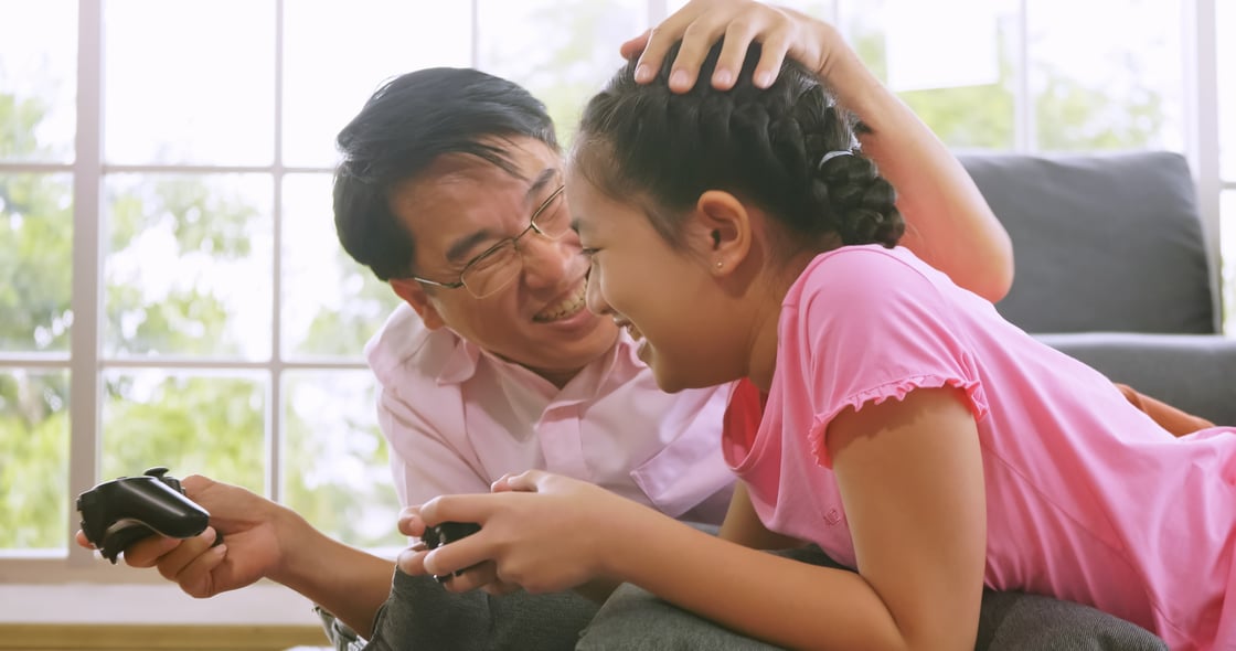 A happy father and daughter playing a video game together.