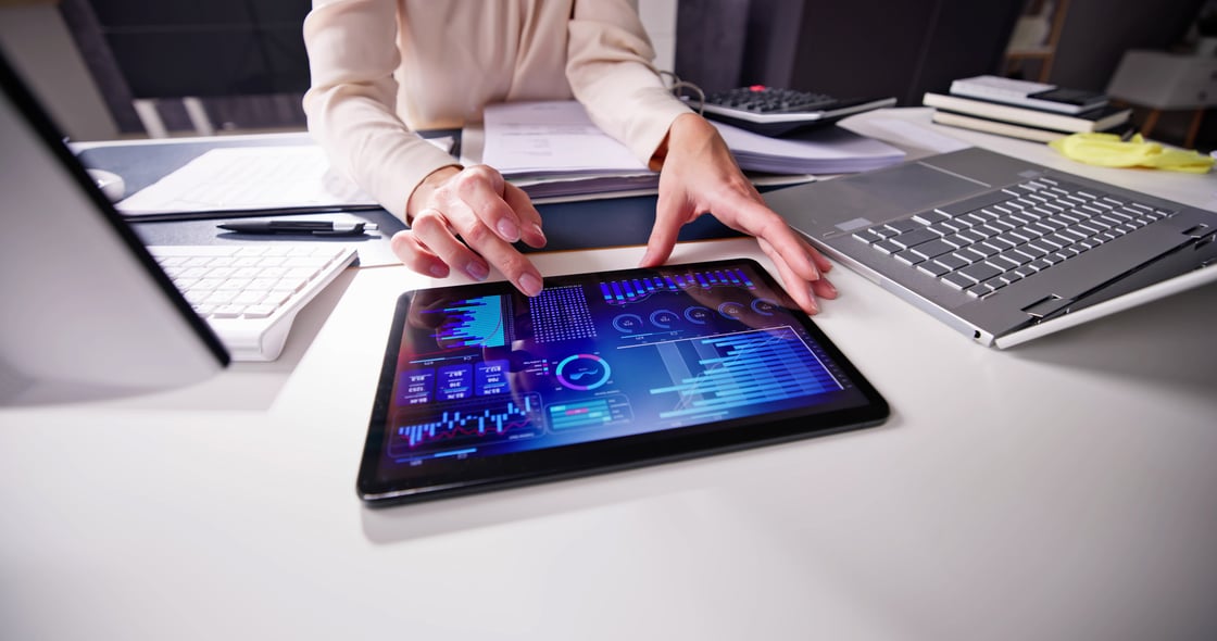 The desktop of a professional woman showing her hands stretch out working on a iPad touchscreen.